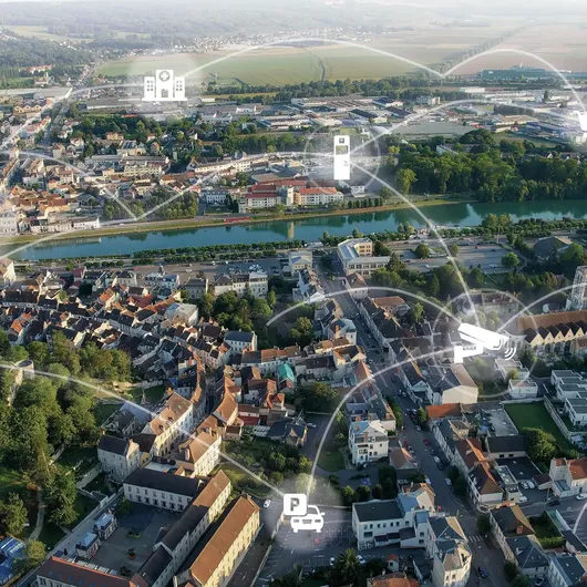 Digitale Vernetzung einer Stadt mit Symbolen für Parken, E-Ladestationen und moderne Parkraumbewirtschaftung