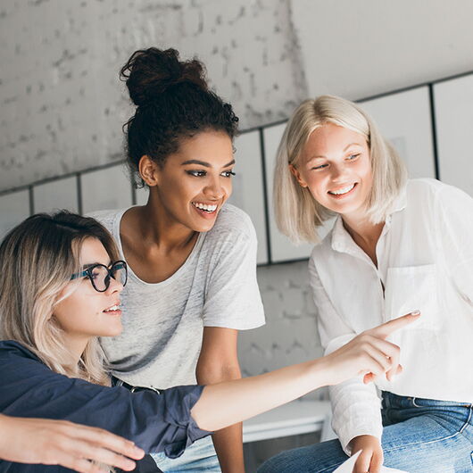Vier Kolleginnen schauen sich etwas auf einem Computer an