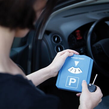 Eine Frau stellt ihre Parkscheibe ein