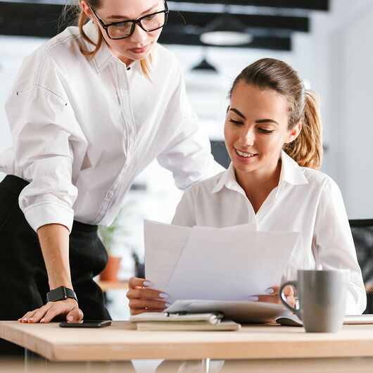 Zwei Kolleginnen schauen sich Papiere an