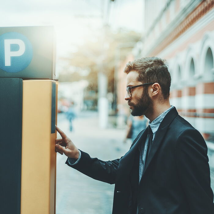 Junger Mann zahlt Parkticket am Automaten